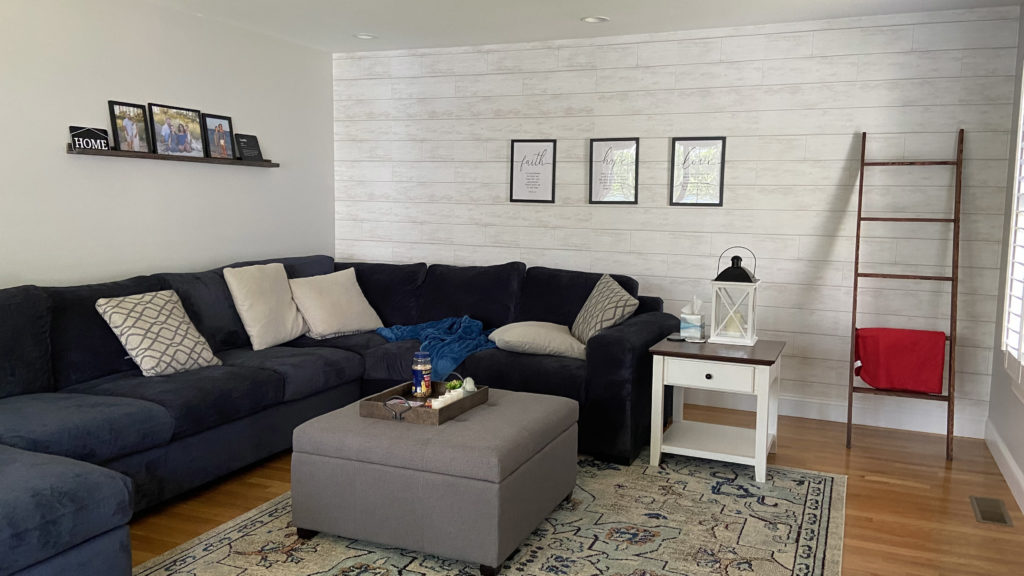 A living room with a blue couch and a decorated wall in the back